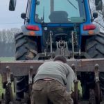 Il trattorista ara la terra vicino al fiume, e l’aratro si è impigliato in una catena